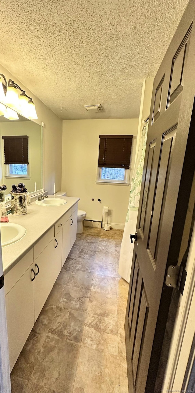 130 Valley Rd, North Branford, CT 06471 - bathroom featuring visible vents, a sink, double vanity, and toilet