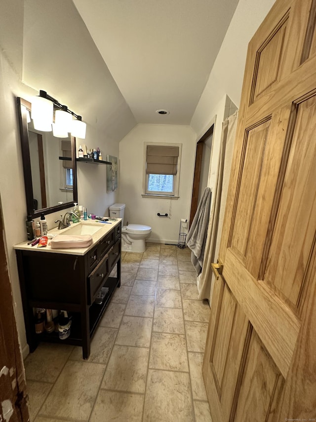 130 Valley Rd, North Branford, CT 06471 - bathroom featuring baseboards, stone tile flooring, toilet, vanity, and vaulted ceiling