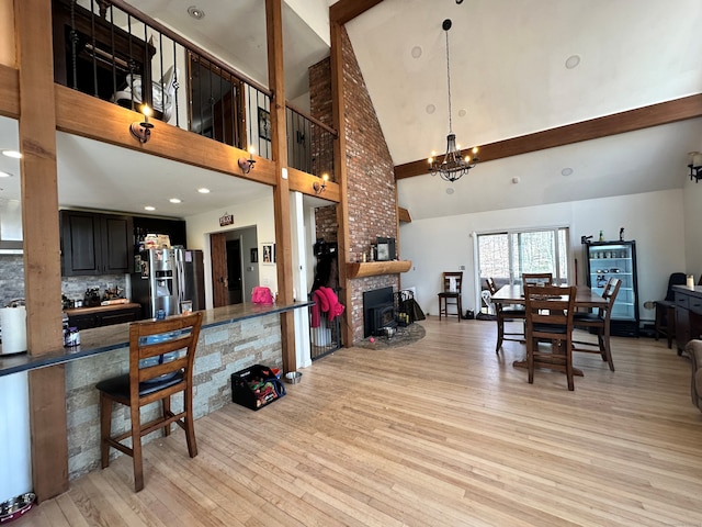 130 Valley Rd, North Branford, CT 06471 - dining room featuring a brick fireplace, light wood-type flooring, a notable chandelier, and a towering ceiling