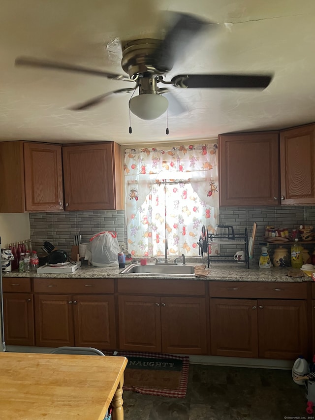 kitchen featuring dark tile patterned flooring, tasteful backsplash, sink, and ceiling fan