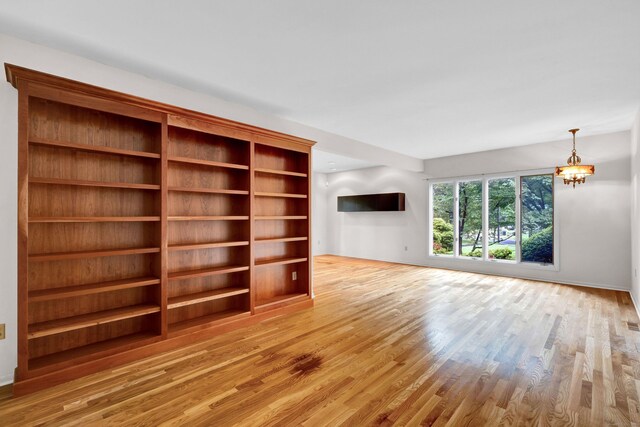 unfurnished living room with a notable chandelier and light hardwood / wood-style floors