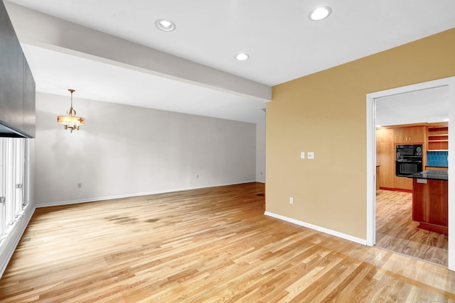 unfurnished living room with beam ceiling, a chandelier, and light wood-type flooring