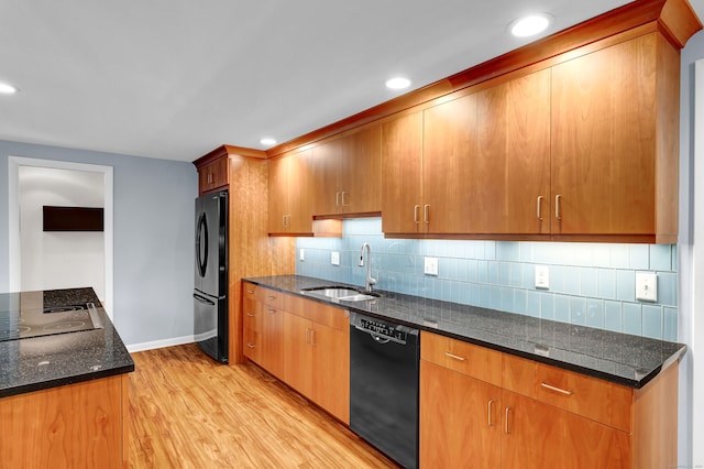 kitchen featuring sink, tasteful backsplash, dark stone counters, light hardwood / wood-style floors, and black appliances