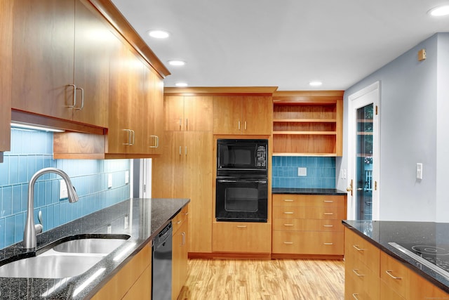 kitchen featuring dark stone countertops, sink, light hardwood / wood-style flooring, and black appliances