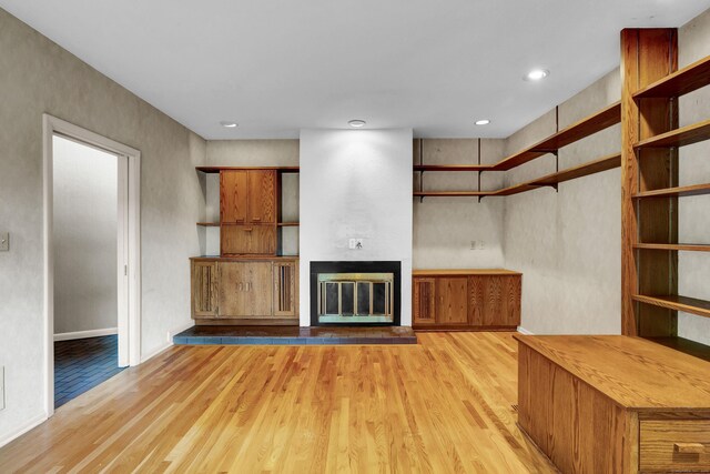 unfurnished living room featuring a large fireplace and light hardwood / wood-style floors