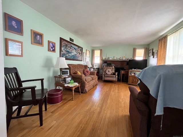 living room featuring light hardwood / wood-style flooring, a brick fireplace, and a wealth of natural light