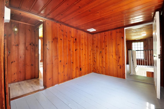 unfurnished room with wooden walls, wooden ceiling, and light wood-type flooring