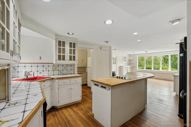 kitchen with tasteful backsplash, sink, dark hardwood / wood-style flooring, white cabinetry, and tile counters