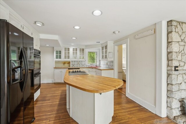 kitchen featuring white cabinetry, backsplash, black appliances, and dark hardwood / wood-style floors