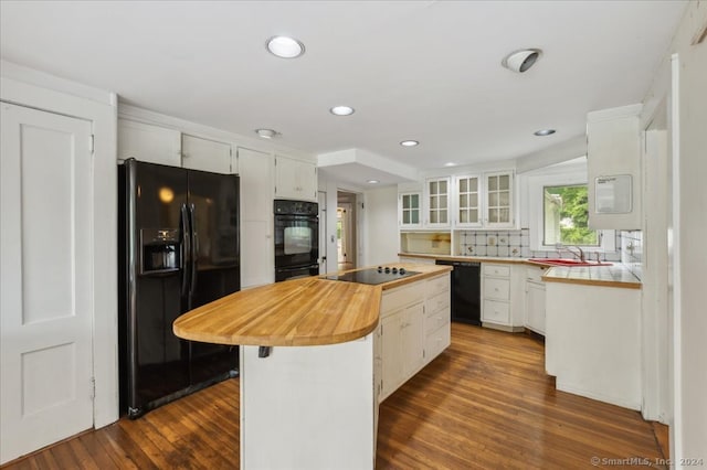 kitchen featuring dark hardwood / wood-style floors, sink, black appliances, a center island, and white cabinetry