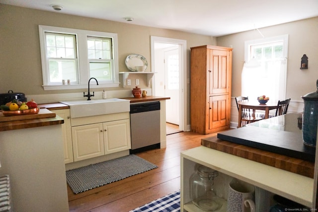 kitchen with sink, radiator, light hardwood / wood-style flooring, wooden counters, and dishwasher