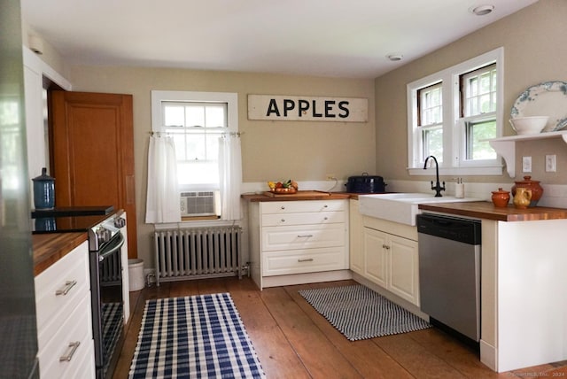 kitchen with butcher block counters, sink, radiator, stainless steel appliances, and hardwood / wood-style floors