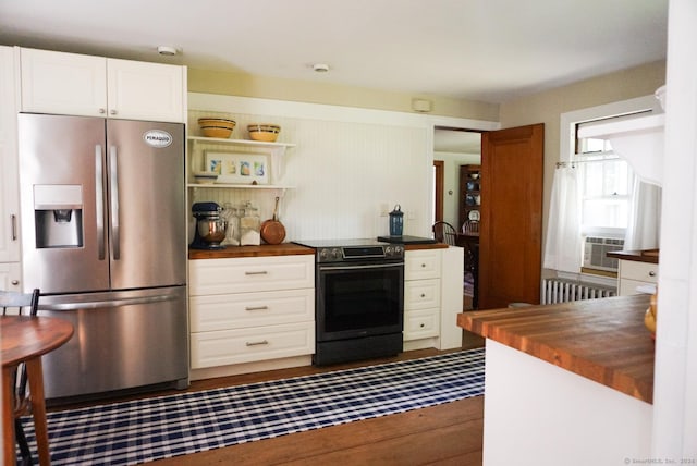 kitchen featuring white cabinetry, butcher block countertops, radiator, and appliances with stainless steel finishes