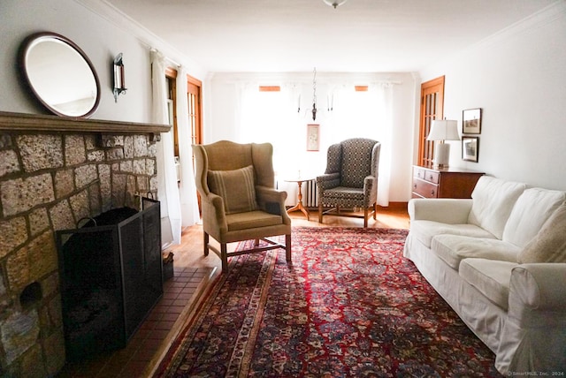 living room featuring hardwood / wood-style floors, crown molding, radiator heating unit, and a brick fireplace