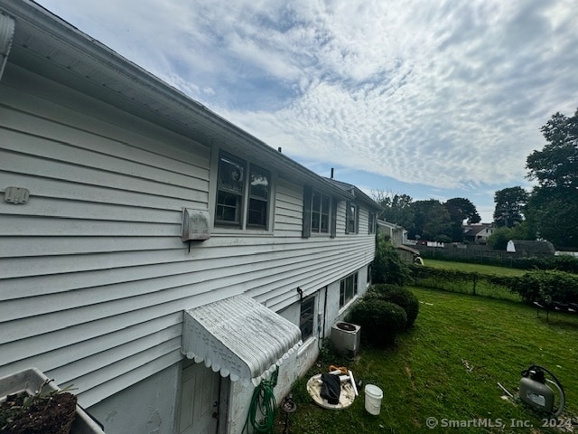 view of home's exterior with cooling unit and a yard