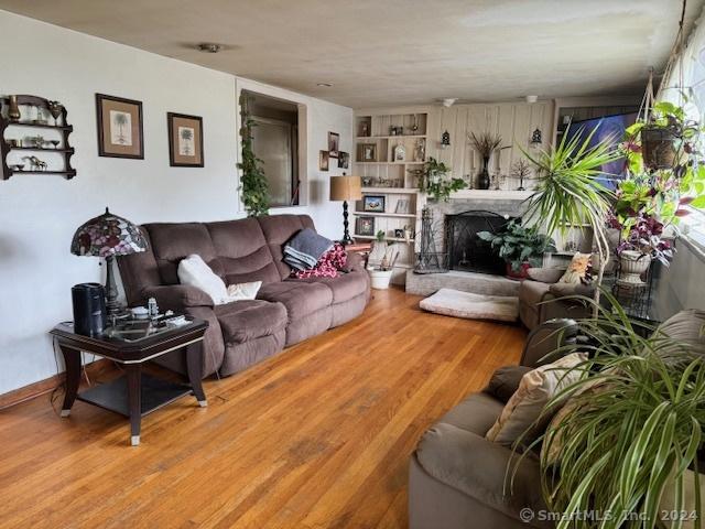 living area with a fireplace with raised hearth and wood finished floors