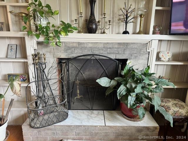 interior details with built in shelves and a fireplace with raised hearth