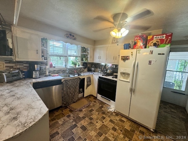 kitchen featuring white appliances, dark tile patterned flooring, decorative backsplash, white cabinetry, and ceiling fan