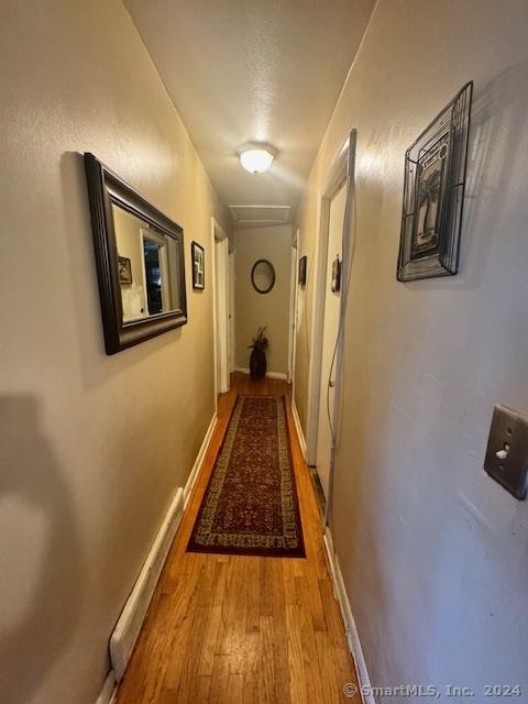 hall featuring attic access, baseboards, and light wood finished floors