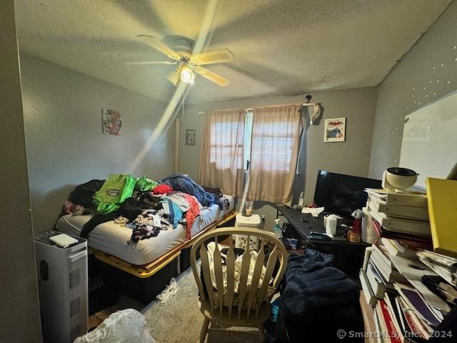 bedroom with a textured ceiling and a ceiling fan