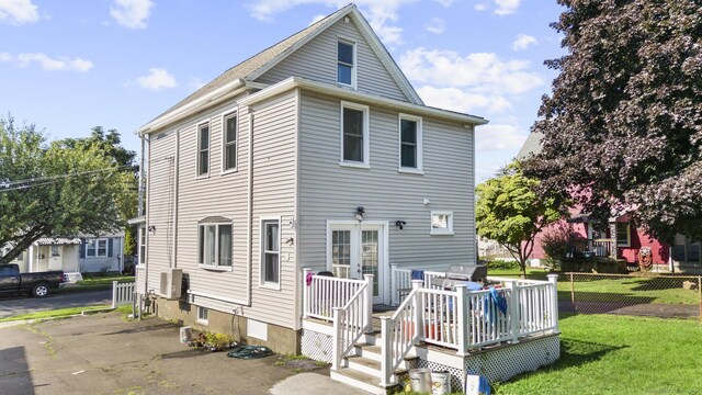 rear view of property with a lawn and a deck