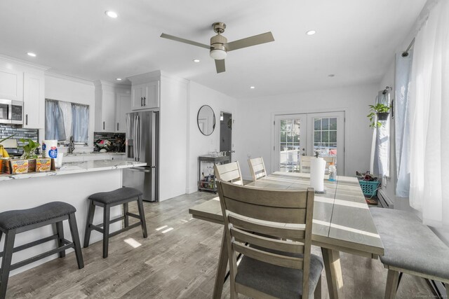 dining room featuring sink, light hardwood / wood-style flooring, ceiling fan, and french doors