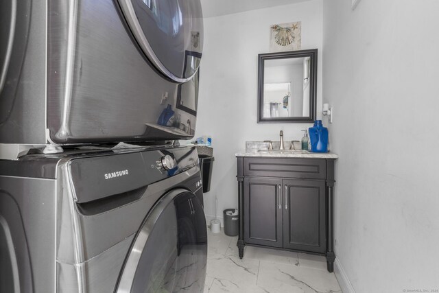 clothes washing area with sink, cabinets, and stacked washer and clothes dryer