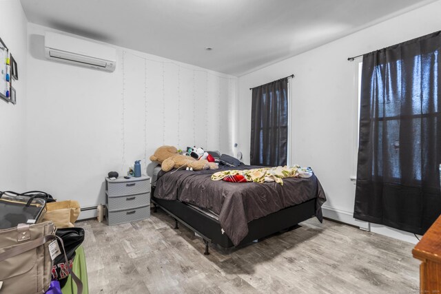 bedroom with hardwood / wood-style floors, a baseboard radiator, and a wall mounted AC