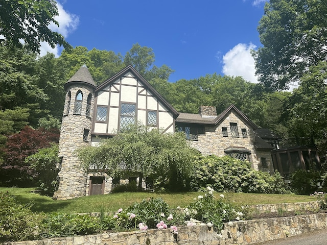 tudor-style house featuring stone siding and a chimney