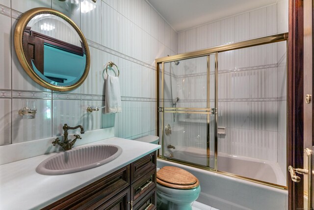 full bathroom featuring tile walls, vanity, bath / shower combo with glass door, and toilet