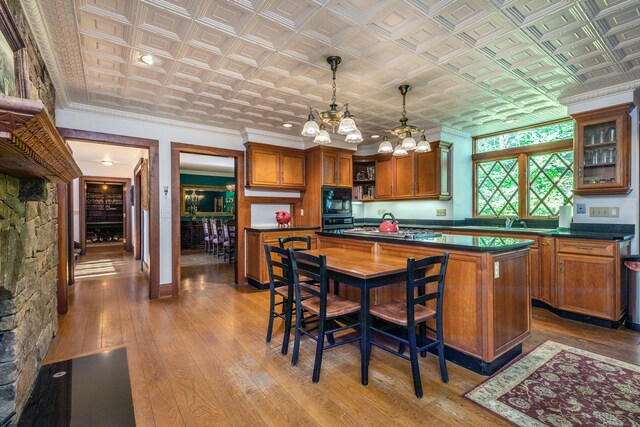 kitchen featuring stainless steel gas cooktop, an inviting chandelier, a kitchen island, pendant lighting, and light hardwood / wood-style floors