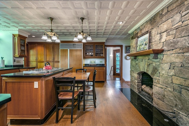 kitchen featuring stainless steel gas stovetop, dark hardwood / wood-style flooring, hanging light fixtures, paneled built in refrigerator, and an inviting chandelier