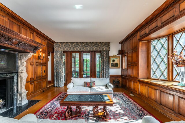 living room featuring dark hardwood / wood-style floors, a fireplace, wooden walls, and french doors