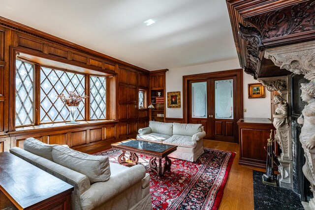 living room featuring french doors, dark wood-type flooring, and wood walls