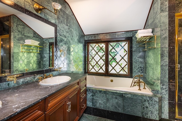 bathroom featuring vanity, lofted ceiling, tile walls, and tiled bath