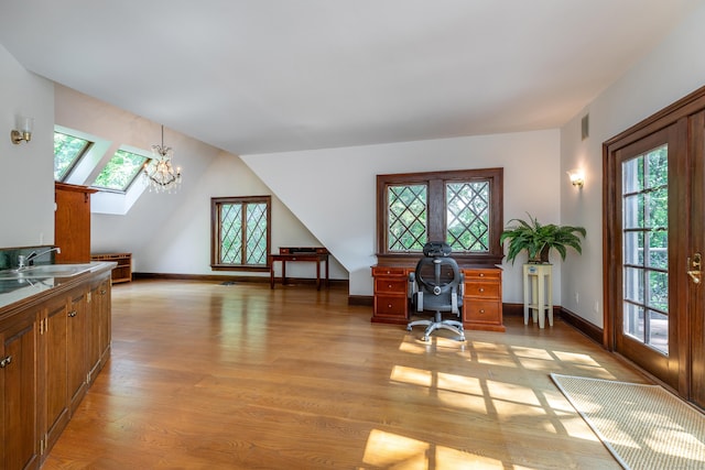 office area featuring sink, plenty of natural light, lofted ceiling with skylight, and a chandelier