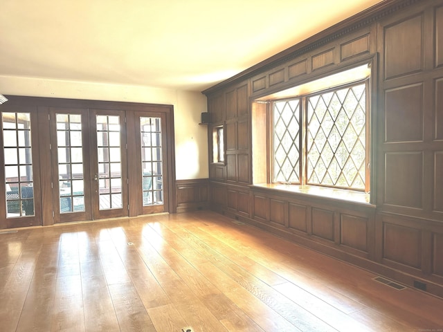 spare room with visible vents, plenty of natural light, french doors, and light wood-type flooring