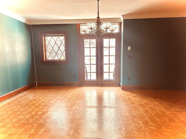 empty room featuring an inviting chandelier, crown molding, french doors, and baseboards