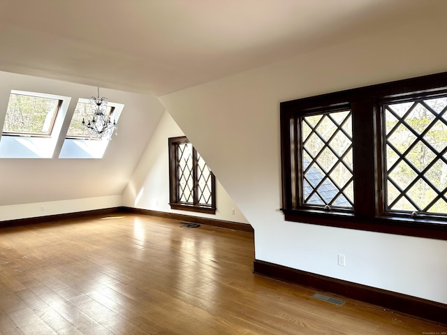 bonus room featuring a wealth of natural light, visible vents, vaulted ceiling, and wood finished floors