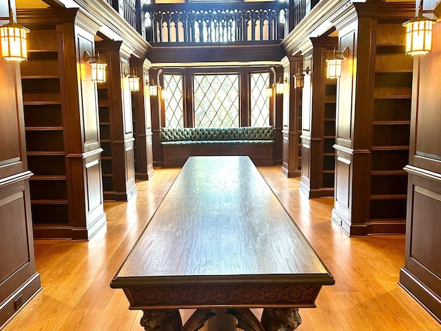 recreation room with light wood-style flooring, a high ceiling, and decorative columns