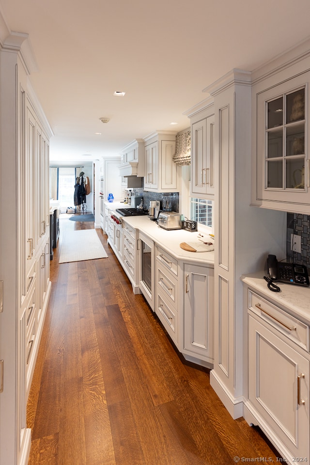 kitchen with backsplash, beverage cooler, dark wood-type flooring, and white cabinets