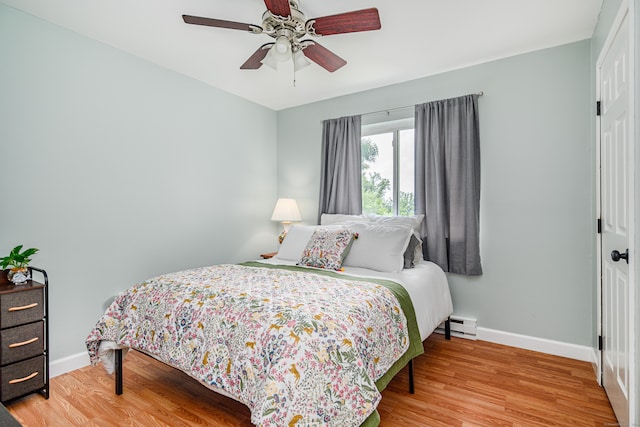 bedroom featuring a baseboard heating unit, light wood-type flooring, and ceiling fan