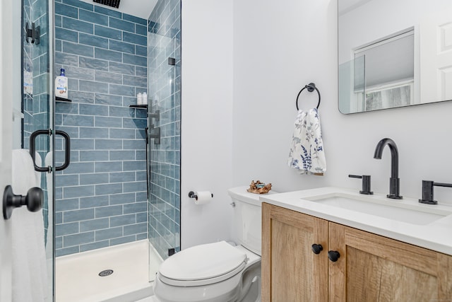 bathroom with a shower with shower door, vanity, and toilet