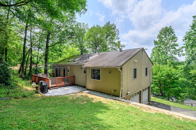 exterior space with a deck, a garage, and a lawn