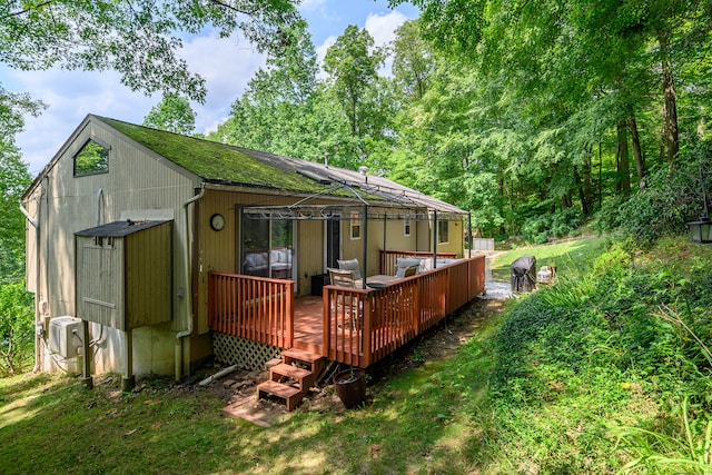 rear view of property featuring a yard, a deck, and cooling unit