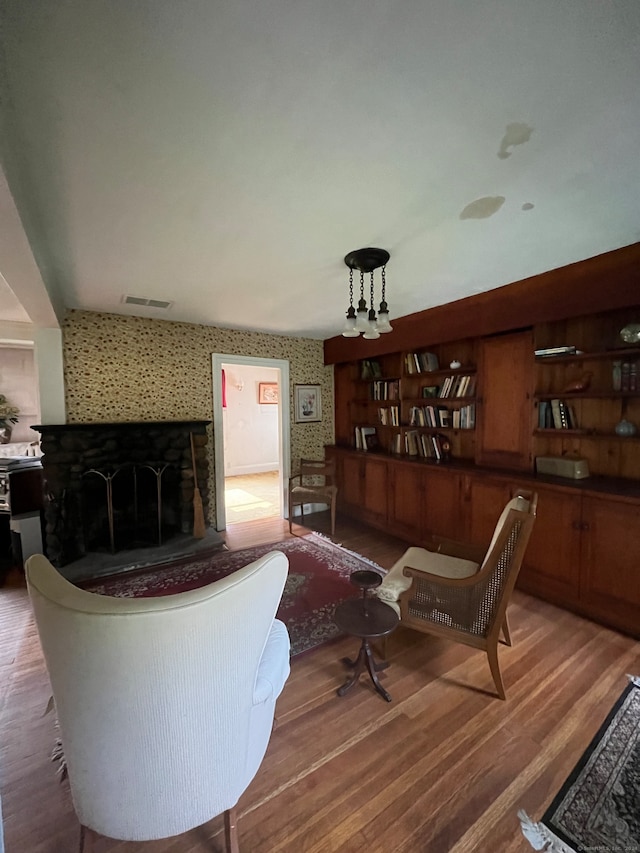 living room with a tiled fireplace and hardwood / wood-style floors