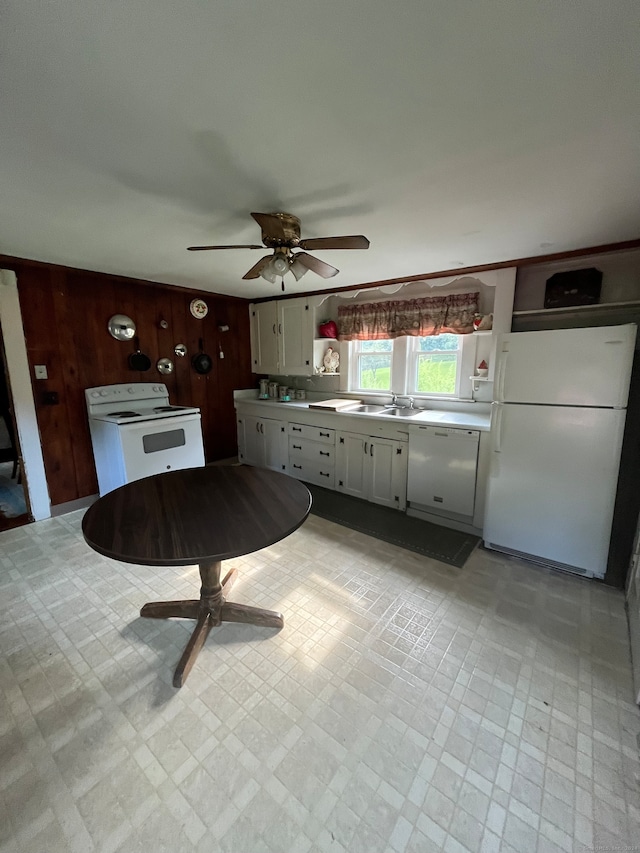 kitchen with wood walls, sink, white cabinetry, white appliances, and ceiling fan