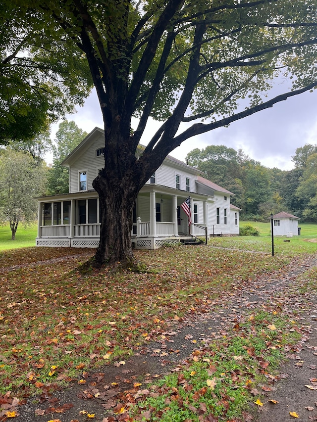 view of front of house featuring a sunroom, covered porch, and a shed