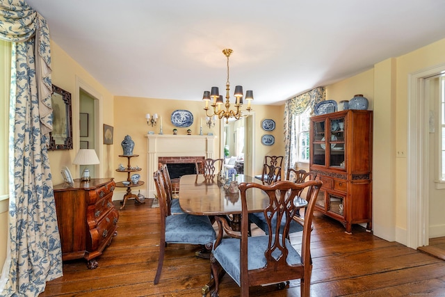 dining space with dark hardwood / wood-style flooring, a fireplace, and a chandelier