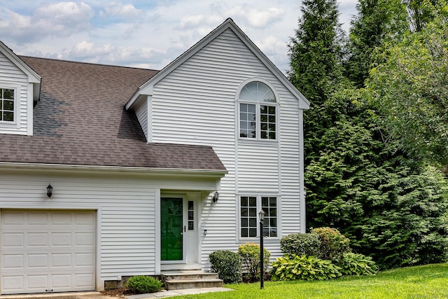 view of front of property featuring a garage and roof with shingles